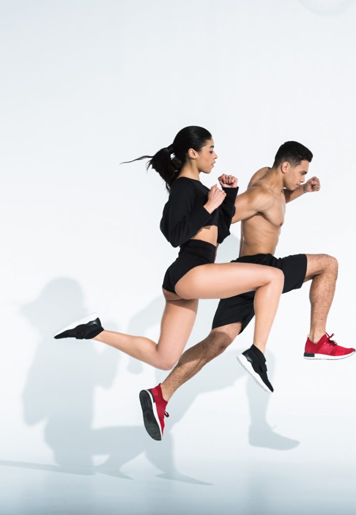 side view of sportive multicultural woman and man in sportswear and sneaker running on white background