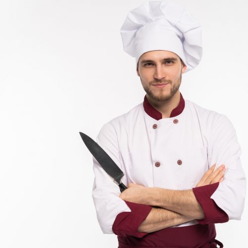 Portrait of a handsome positive male chef cook holding knifes isolated on a white background