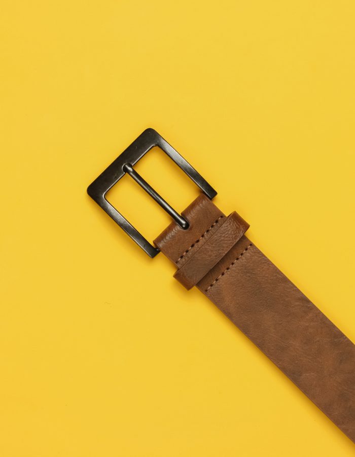 Leather brown belt on yellow background