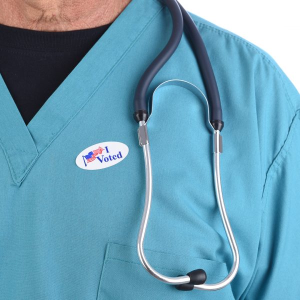 Closeup of a doctor with an I Voted sticker on his surgical scrubs.